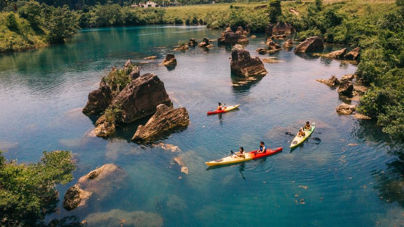 Activité de kayak à Quang Binh, Vietnam, sur une rivière tranquille entourée de paysages verdoyants